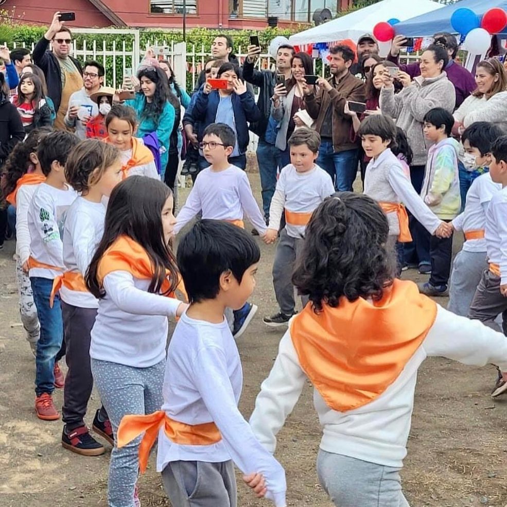 Niños y niñas bailando en círculo durante una actividad comunitaria